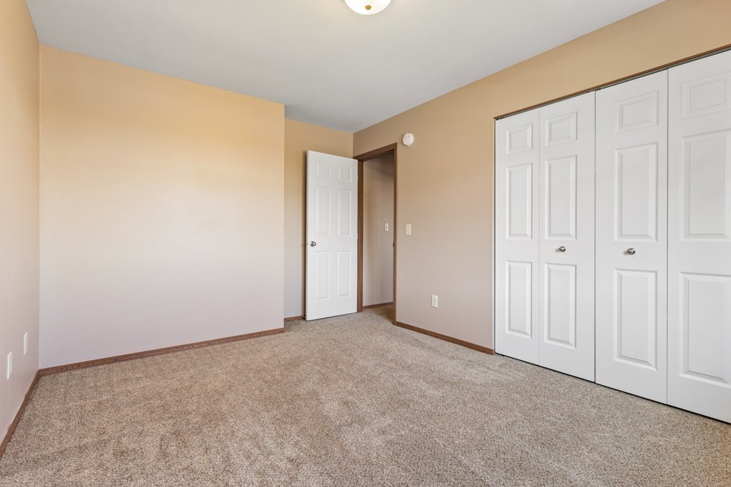 A room with a carpeted floor and white doors.