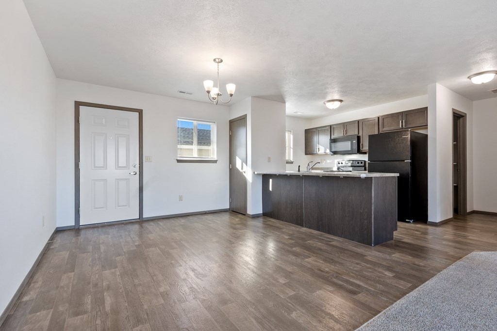 A spacious living room with a kitchen area in the background.
