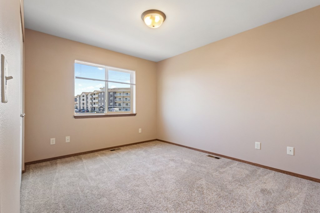 A room with a window showing a view of buildings outside.