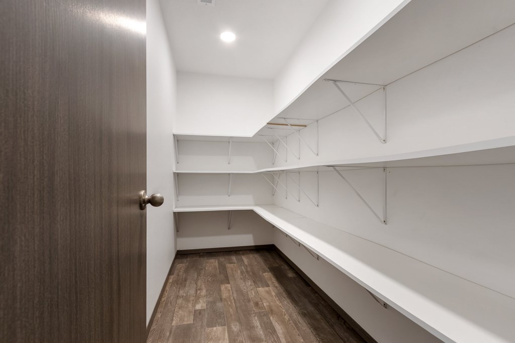 A hallway with a brown door and white walls.