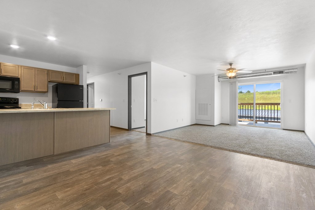A spacious living room with a kitchen area and a view of the outdoors.