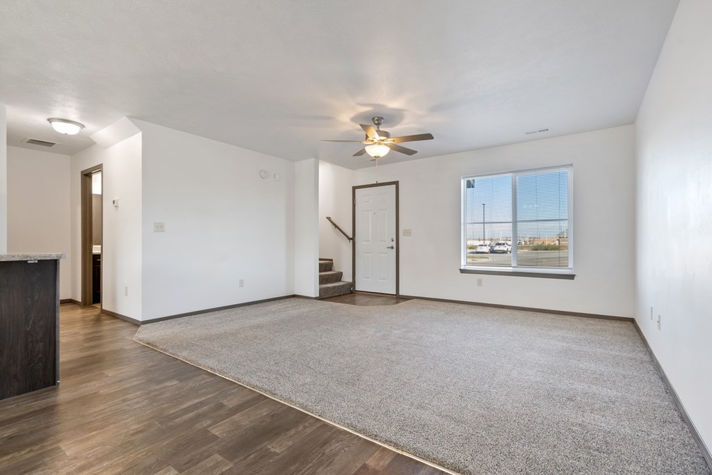 A spacious room with a ceiling fan and a large rug on the floor.