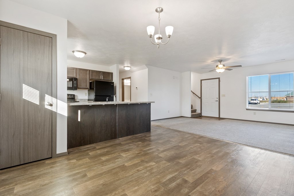 A spacious living room with a kitchen area in the background.