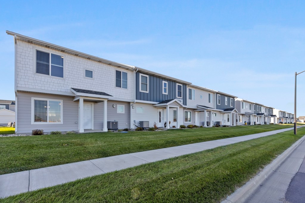 A row of houses with a sidewalk in front.