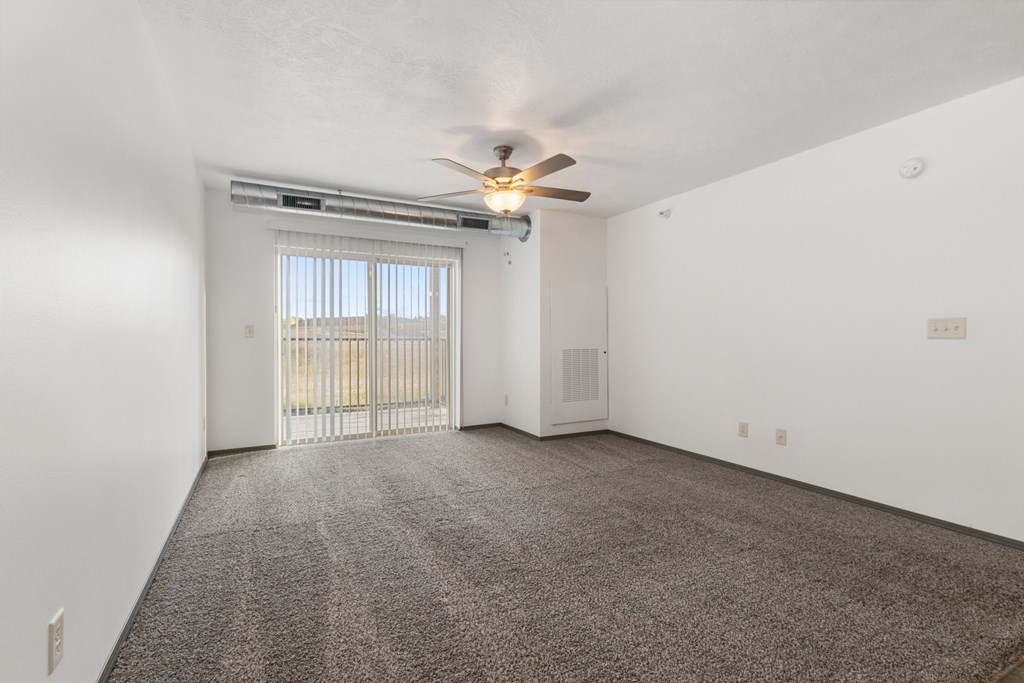 A room with a ceiling fan and a sliding glass door leading to a balcony.