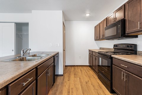 A kitchen with dark wood cabinets and a black stove top oven.