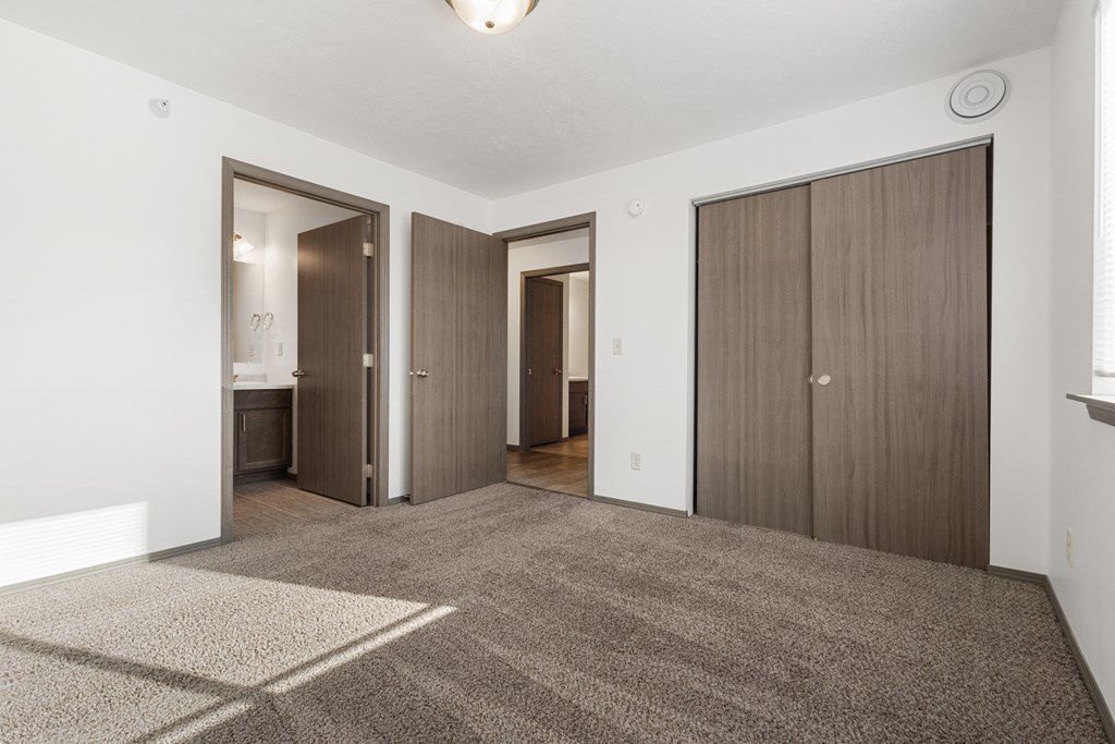 A room with a carpeted floor and three doors.