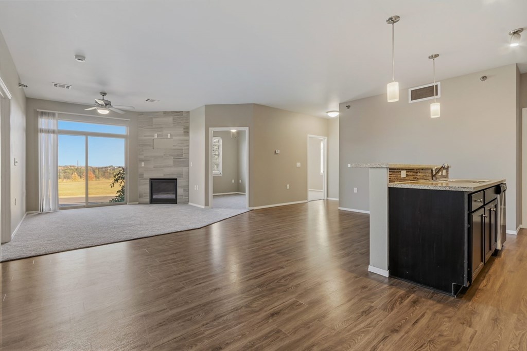 A spacious living room with a fireplace and a kitchen area with a countertop and cabinets.