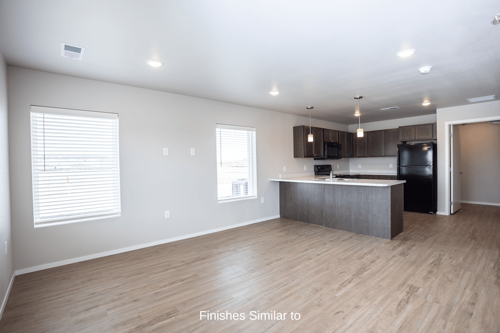 a kitchen and living room with white walls and wood flooring