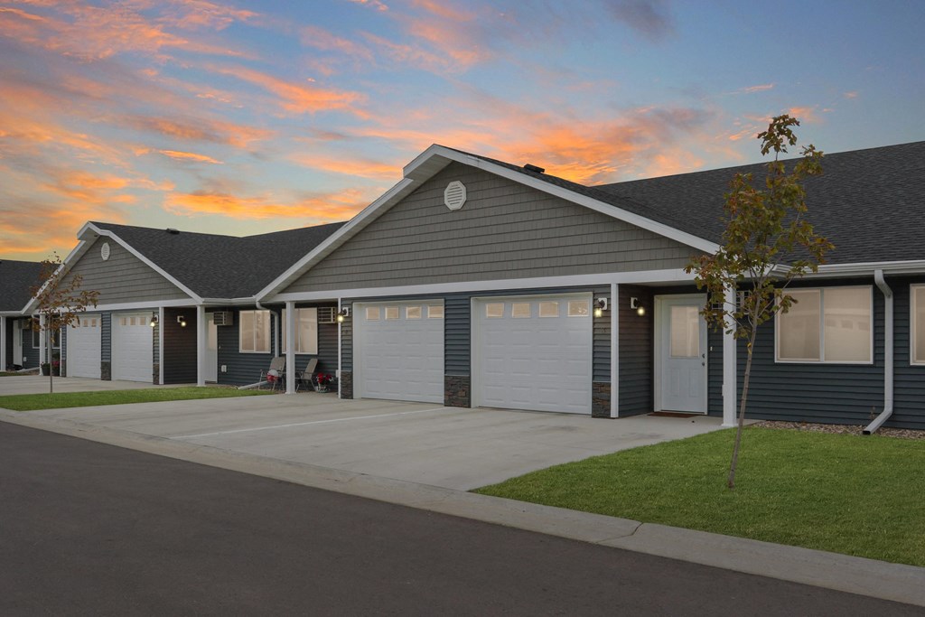 the front of a house with garage doors at sunset