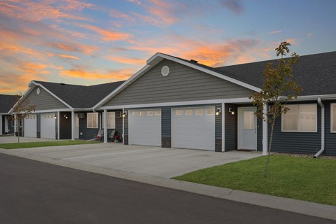the front of a house with garage doors at sunset