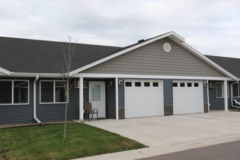 the front of a blue house with two garage doors