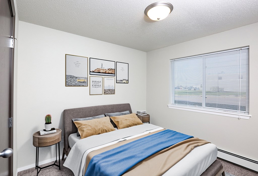A bedroom with a bed, pillows, a small table, and pictures on the wall.
