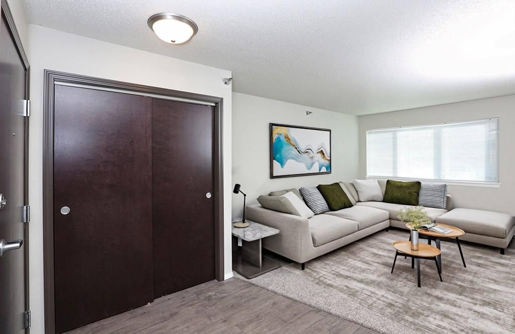 A living room with a couch, a coffee table, and a painting on the wall.
