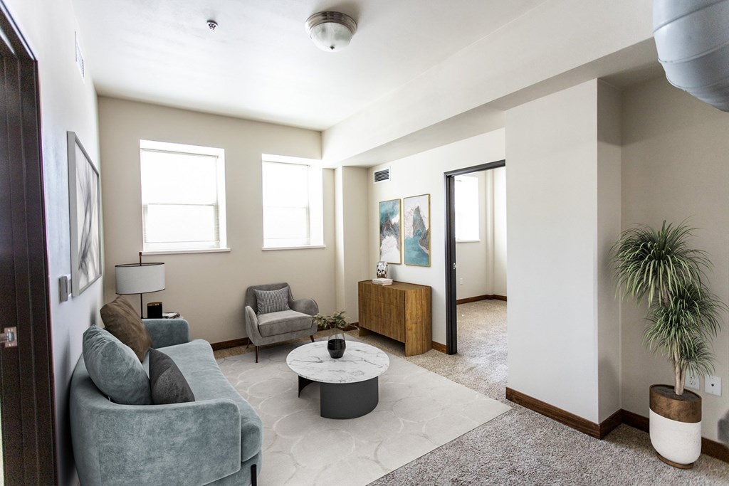 A living room with a grey couch, a white coffee table, and a plant.