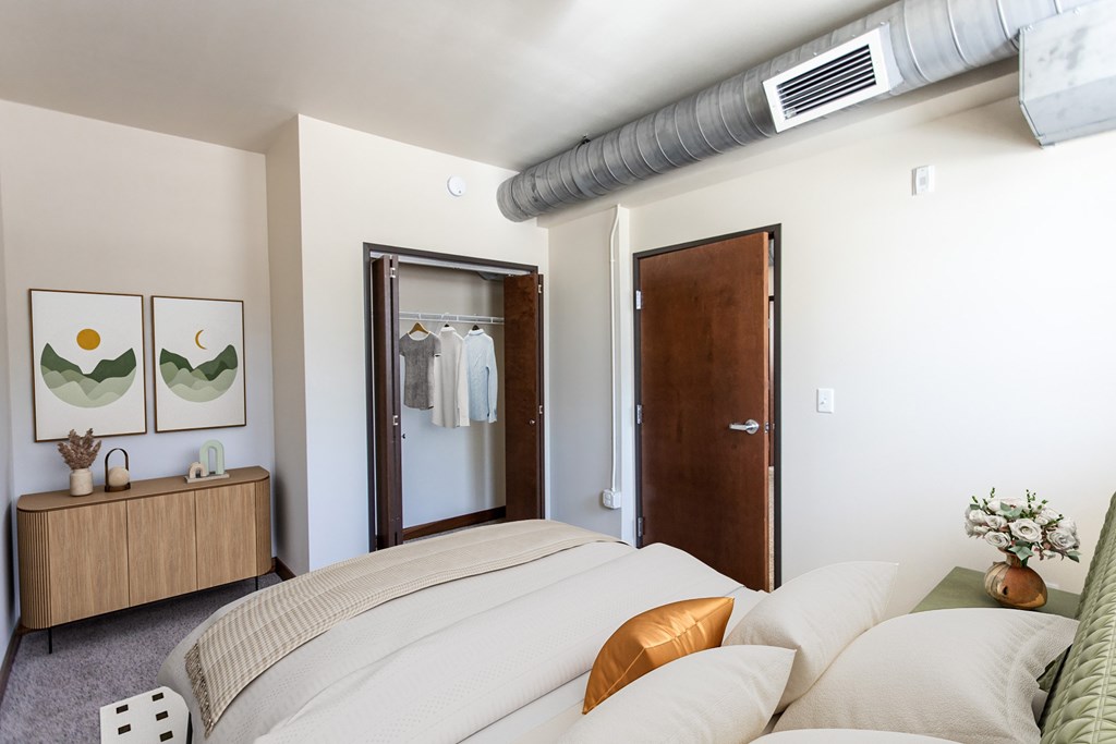 A bedroom with a bed, nightstand, and a painting on the wall.