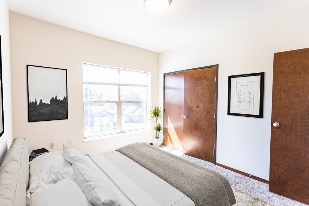 A bedroom with a bed, a window, and two pictures on the wall.