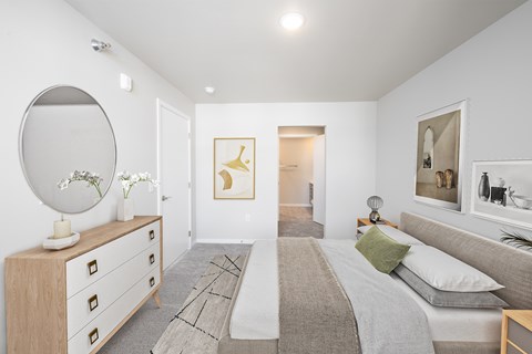 A bedroom with a bed, dresser, mirror, and artwork.