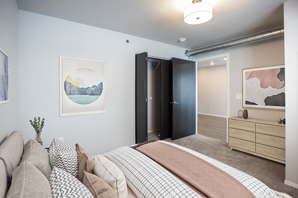 A bedroom with a bed, couch, and artwork on the walls.