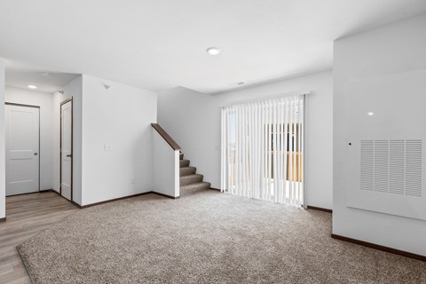 a renovated living room with white walls and a staircase with a glass door