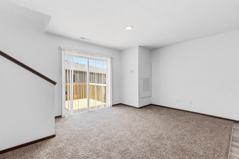 an empty living room with a door to a balcony