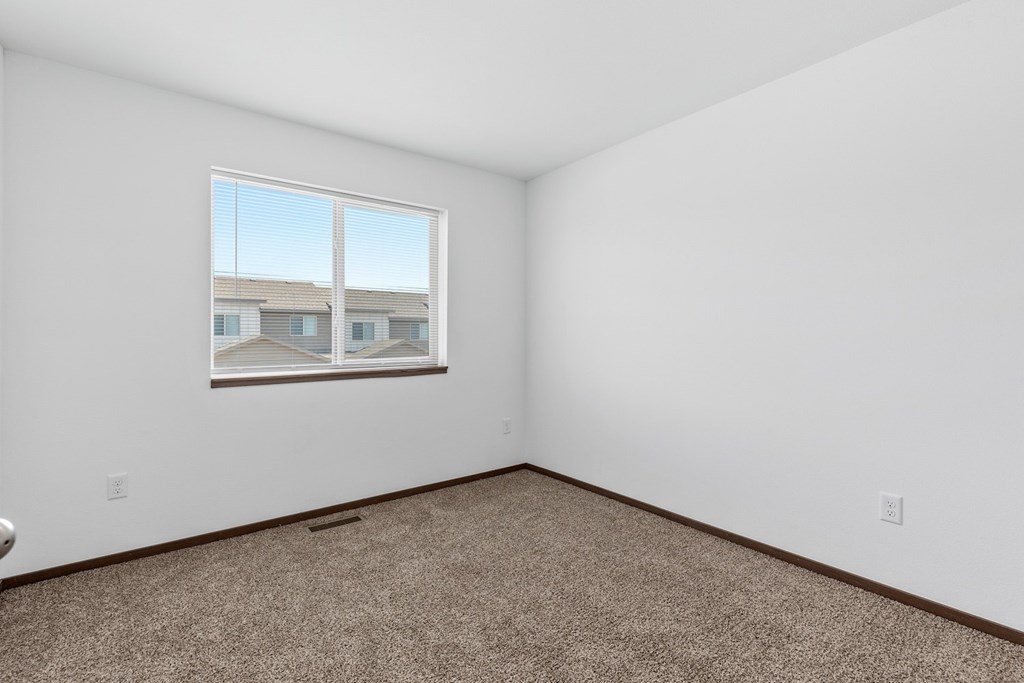 the living room of an apartment with carpet and a window