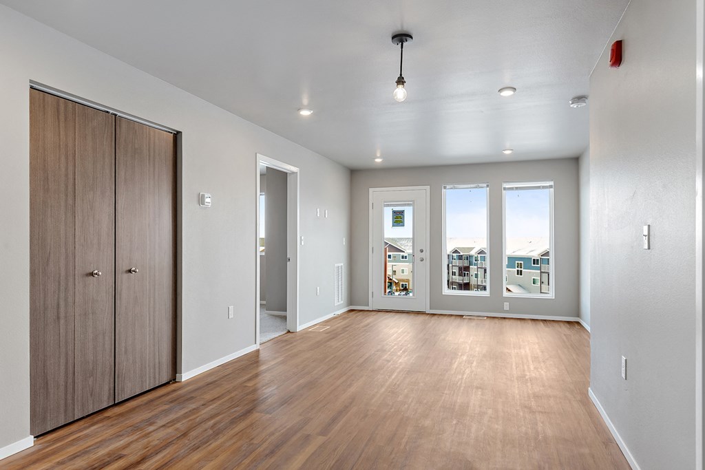 an empty living room with a wooden floor and windows