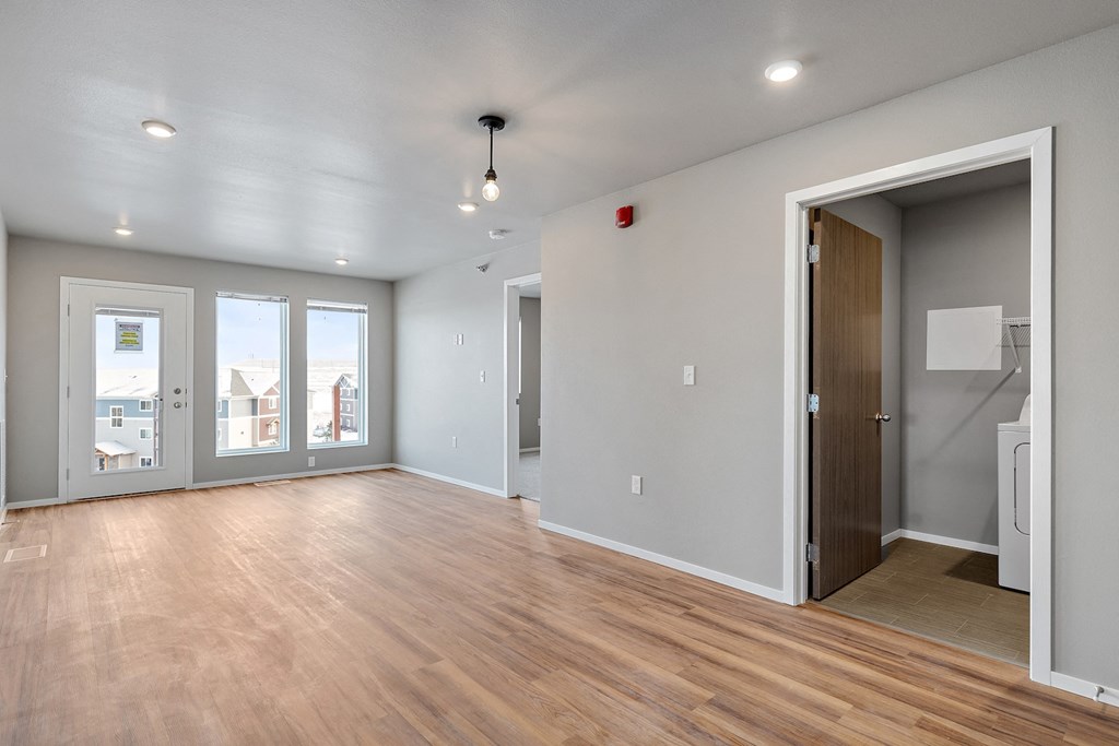 an empty living room with wood flooring and a door to a hallway
