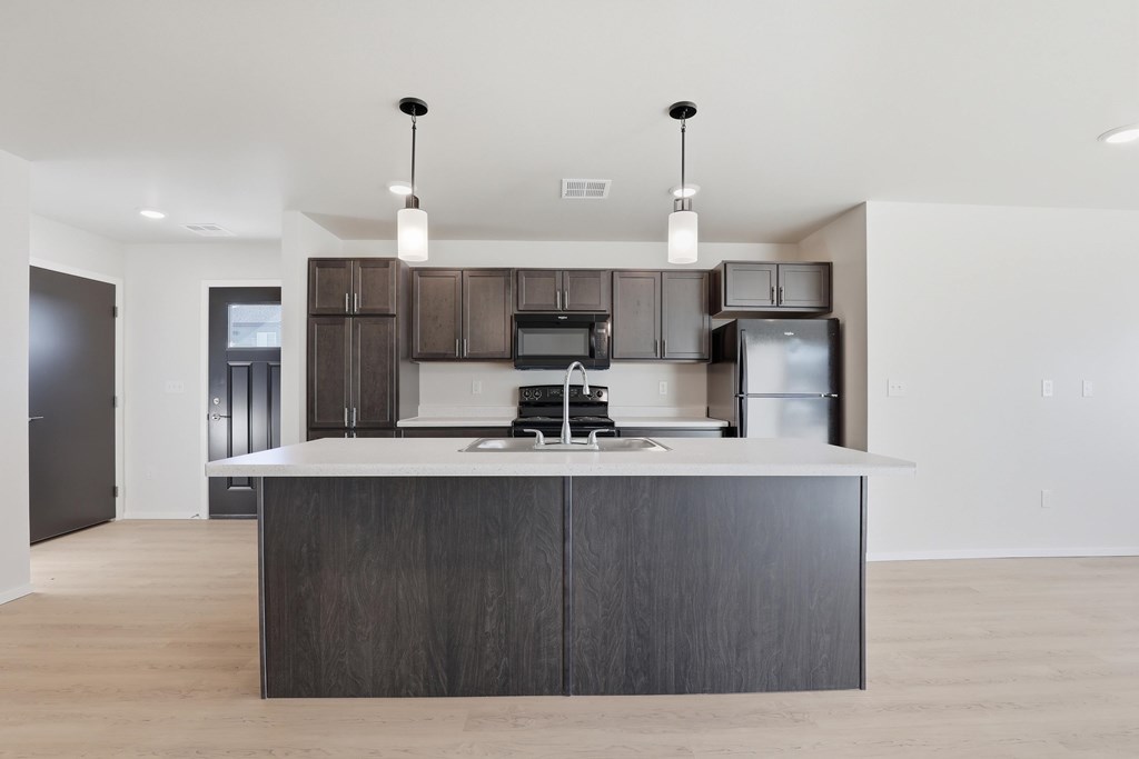 A modern kitchen with a dark wood island and stainless steel appliances.