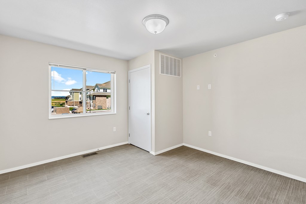 an empty living room with a window and a door to a closet