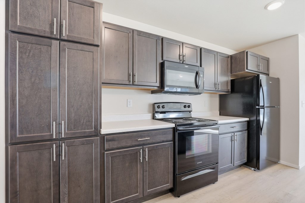 A kitchen with dark brown cabinets and stainless steel appliances.