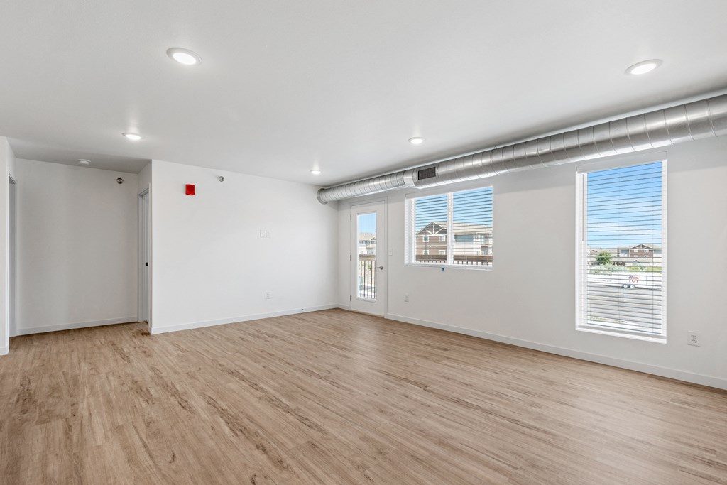 the living room of an apartment with a wood floor and white walls