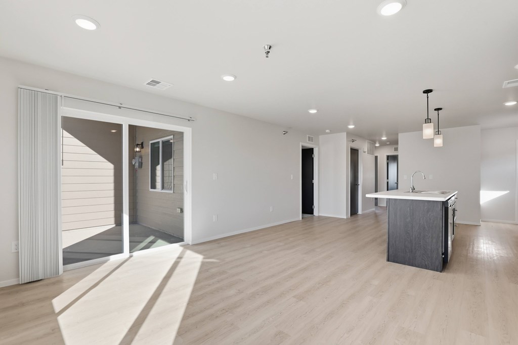 A large, empty room with a sliding glass door leading to a balcony.