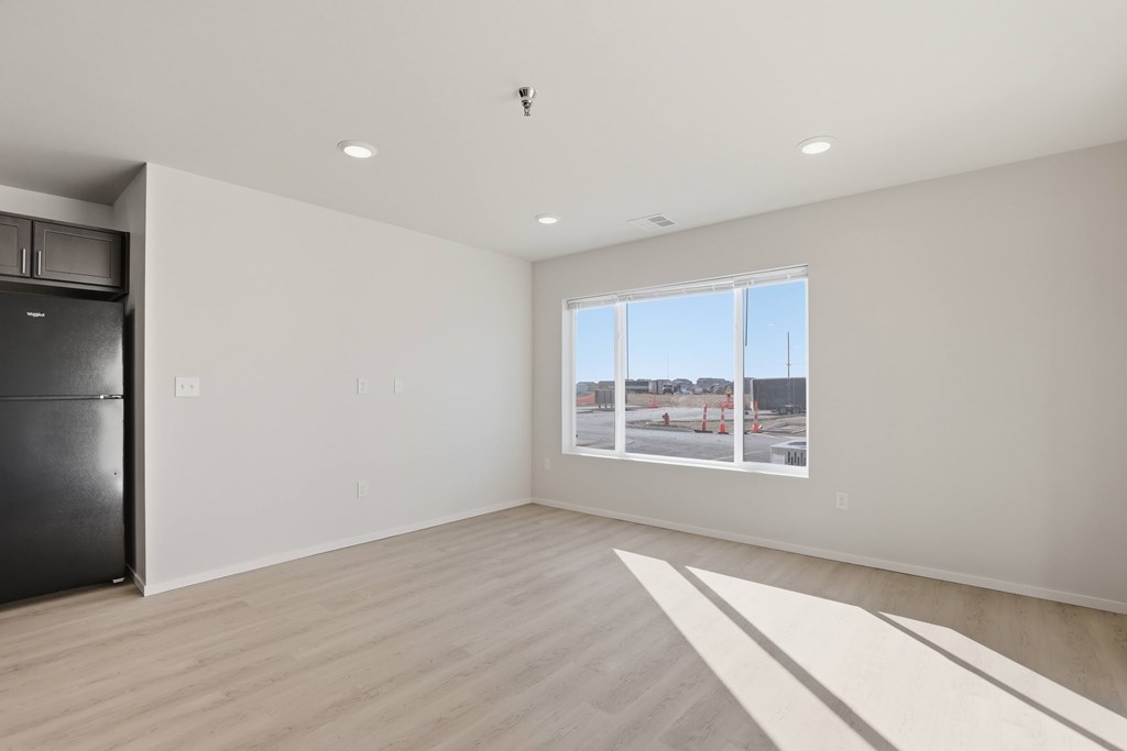 A spacious room with a large window overlooking a construction site.