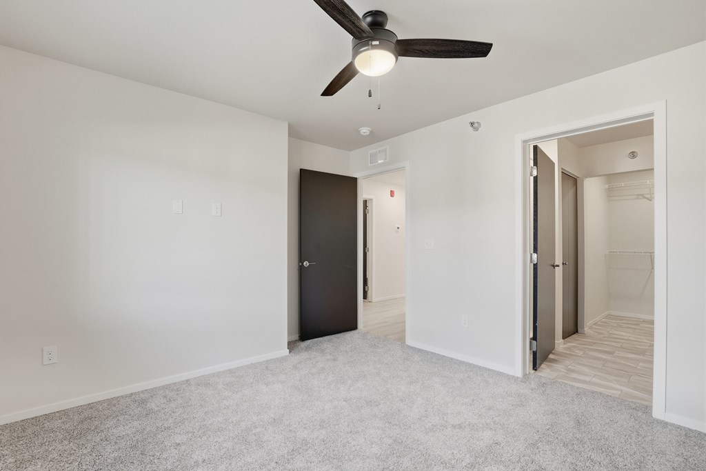 A room with a ceiling fan and two doors.