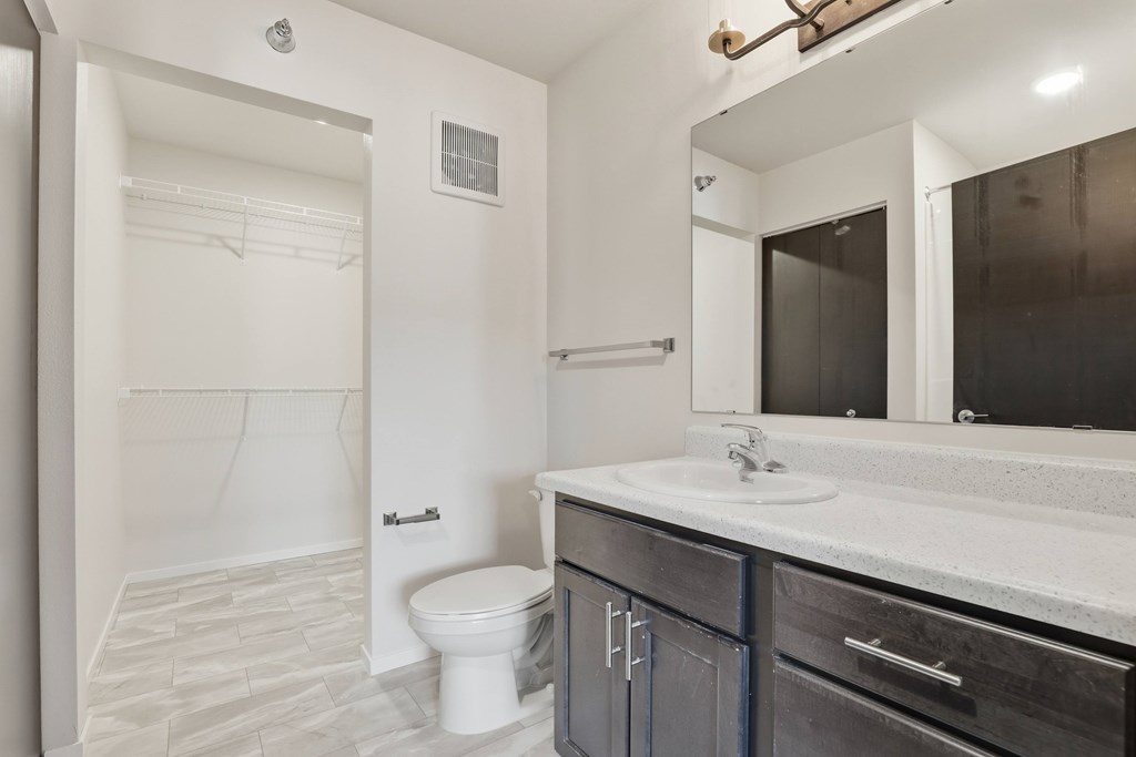A bathroom with a toilet, sink, and mirror.