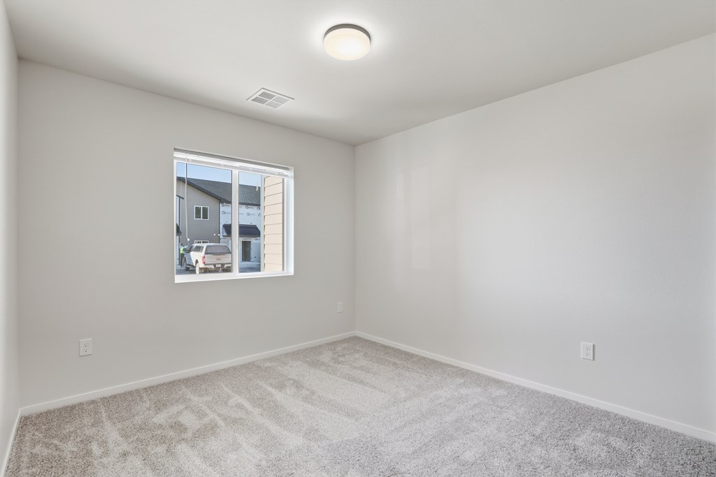 A room with a window showing a view of a building and a car outside.