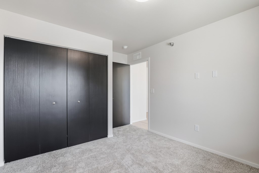 A room with a white wall and a grey carpet.