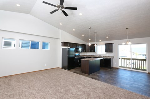 a living room with a kitchen and a ceiling fan