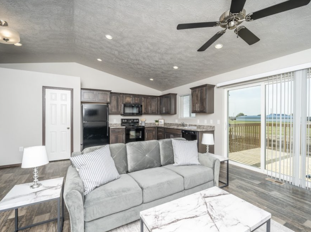 a living room and kitchen with a couch and a ceiling fan