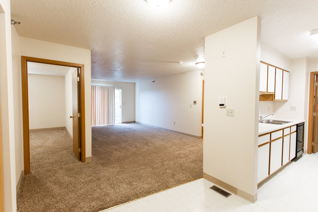 an empty living room and kitchen with an open door to the bathroom