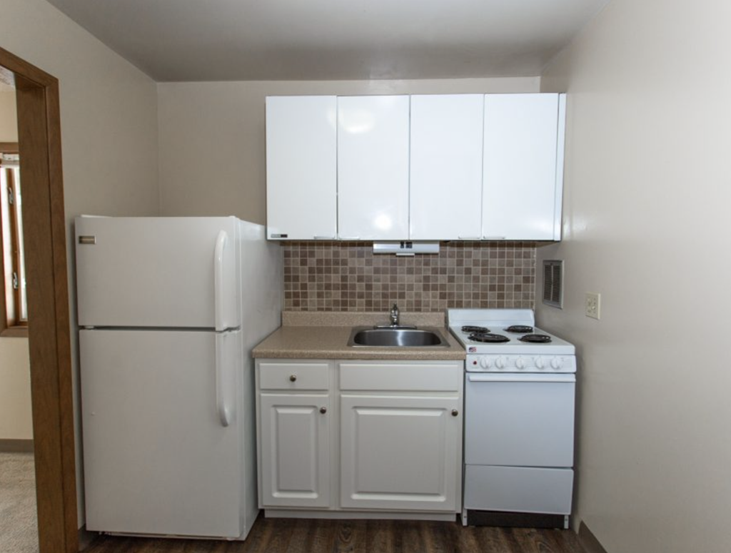an empty kitchen with a stove refrigerator and sink