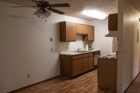an empty kitchen with wooden cabinets and a ceiling fan