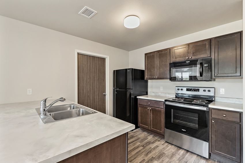 a kitchen with black appliances and white countertops and a sink