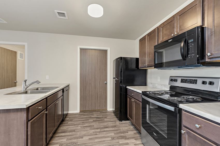 an empty kitchen with black appliances and wooden cabinets