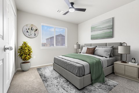A bedroom with a bed, nightstand, and a plant.