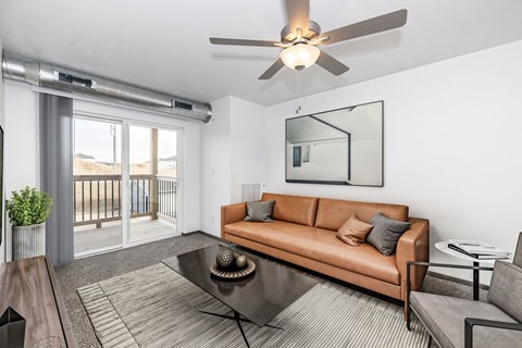 A living room with a brown couch, a coffee table, and a ceiling fan.