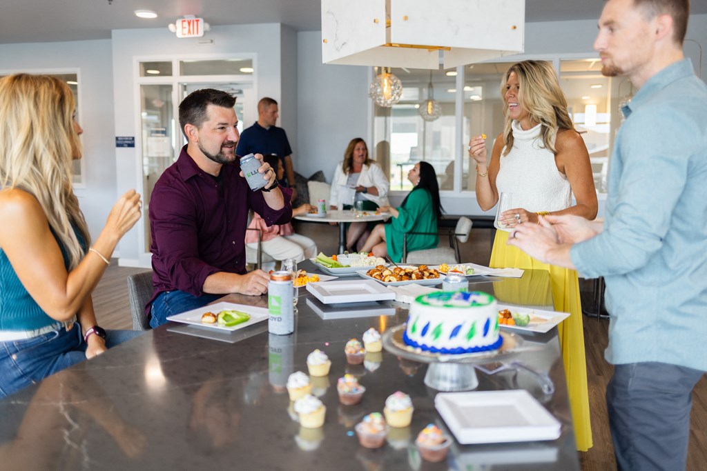 a group of people standing around a table with a birthday cake