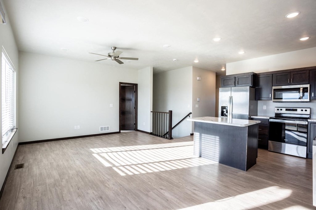 a large living room with a kitchen and a ceiling fan