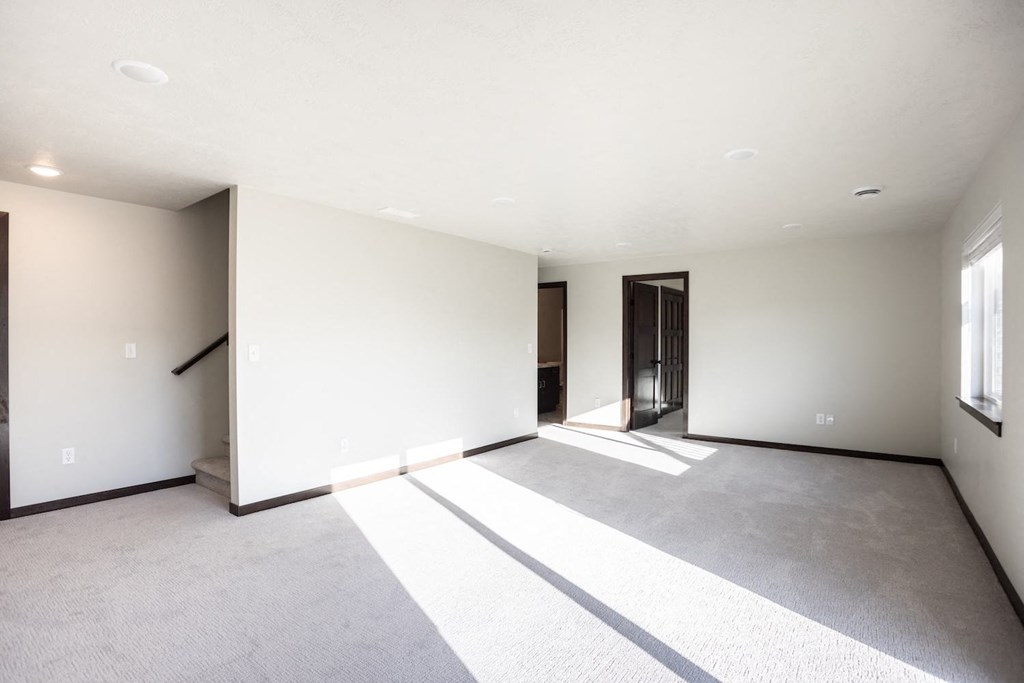 an empty living room with white walls and grey carpet